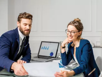 Man-and-woman-at-office-desk-looking at paper